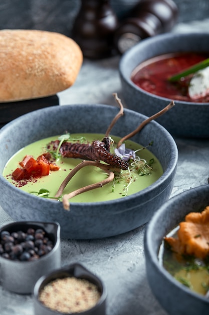 Plate with asparagus soup with octopus, a plate of traditional borscht with sour cream, a plate with mushroom soup 