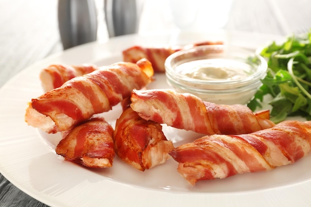 Plate with bacon wrapped chicken nuggets on table closeup