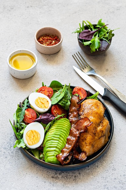 Plate with baked chicken fillet with bacon, fresh vegetables, salad. Popular keto diet, concept