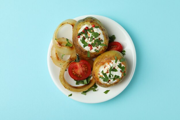 Plate with baked potato on blue background.