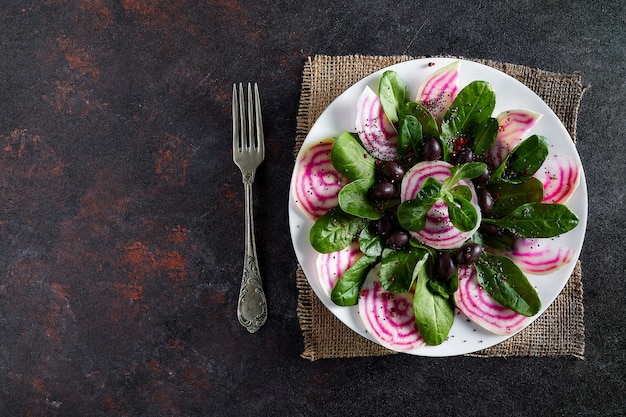 Plate with beet salad, from root to leaves, with some corn salad and black olives