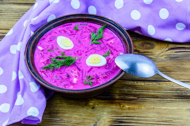 Plate with beet soup on a wooden table