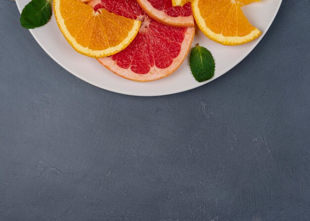 A plate with bite of citrus fruits and green leafs, with a copy space