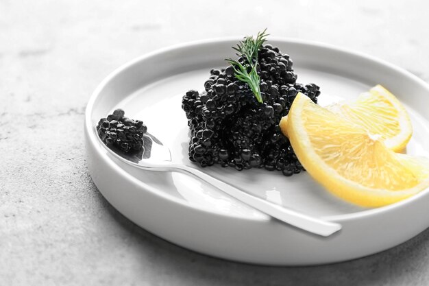 Photo plate with black caviar and slices of lemon on table