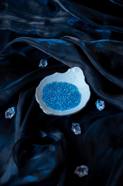 Photo plate with blue beads on a dark shiny fabric