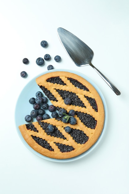 Plate with blueberry pie and spatula on white