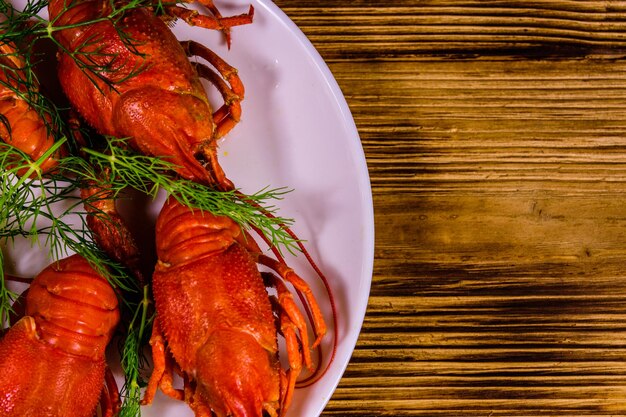 Plate with boiled crayfishes on rustic wooden table Top view