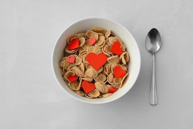 Тарелка с хлопьями для завтрака и видом сверху красных сердец. Здоровый завтрак, концепция. Открытка ко дню святого валентина