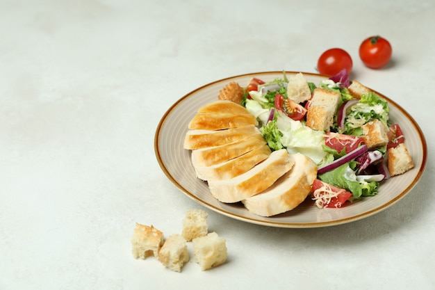 Plate with Caesar salad and ingredients on white