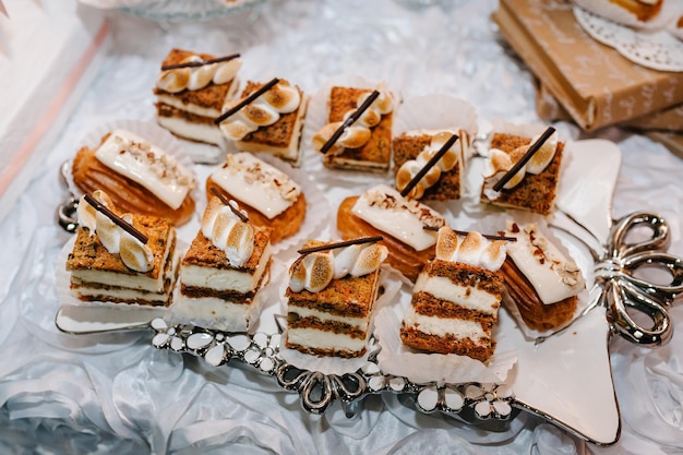 Plate with cakes decorated dessert table for a party Delicious sweets on buffet Table with muffins candy for a party goodies on wedding banquet area Close up candy bar flat lay top view