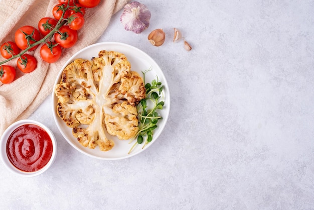 Piatto con verdure bistecca di cavolfiore e salsa di pomodoro su fondo bianco cibo vegetariano sano