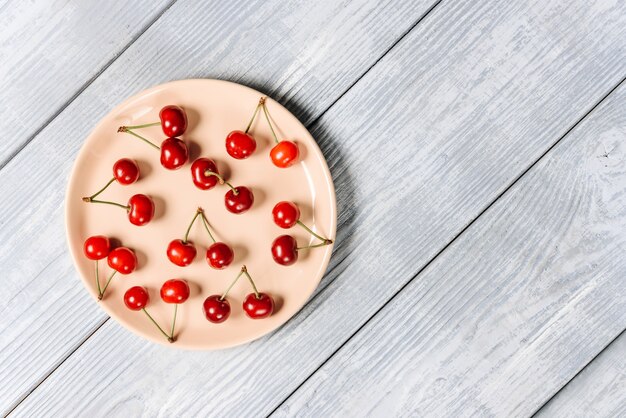 Photo plate with cherries on white wooden