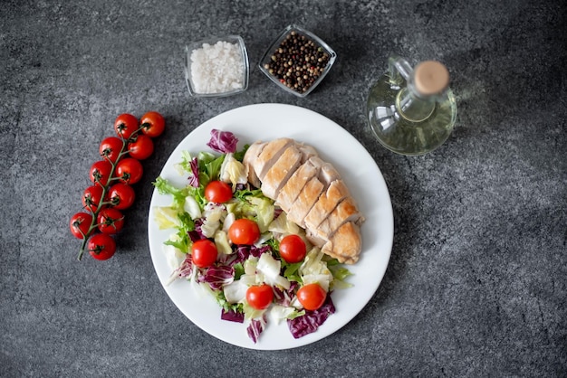 plate with chicken fillet and salad with vegetables on a stone background