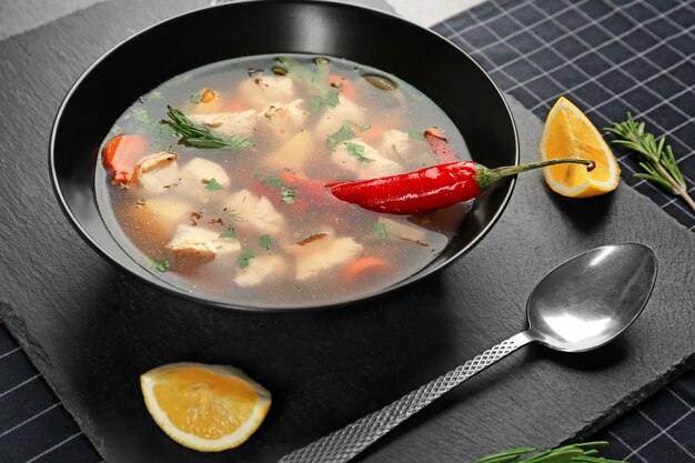 Plate with chicken soup and chili pepper on table