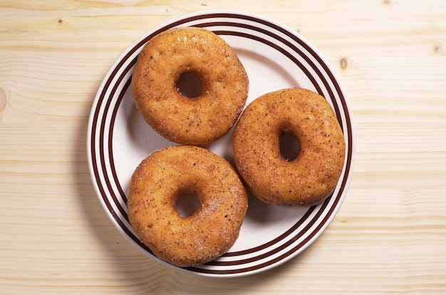 Plate with classic donuts on wooden background, top view