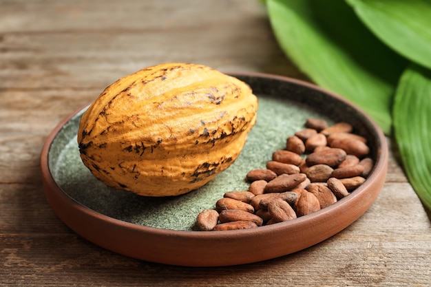 Plate with cocoa pod and beans on table closeup