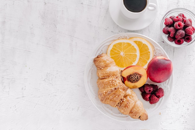 Plate with croissant and fruits