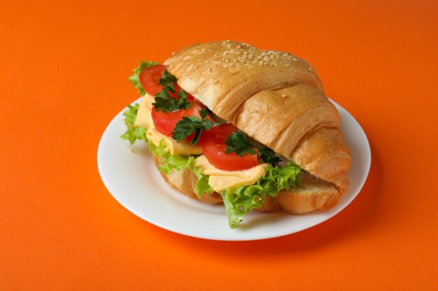 Plate with croissant sandwich on orange