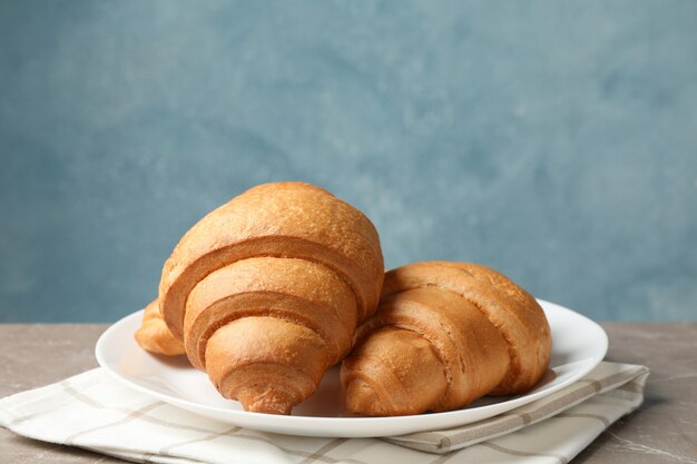 Plate with croissants on grey table, space for text