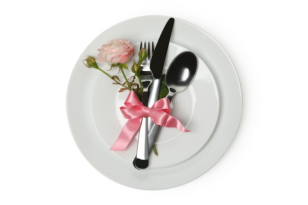 Тарелка со столовыми приборами, розовым бантом и розой, изолированные на белом фоне