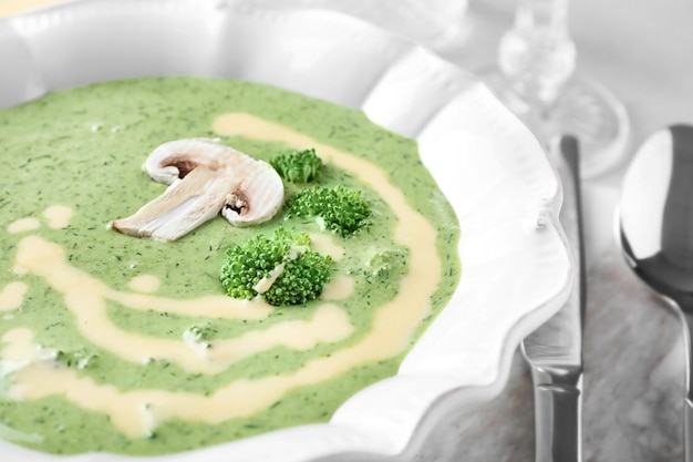 Plate with delicious broccoli cheese soup on table closeup