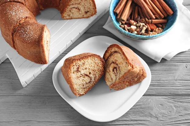 Plate with delicious cinnamon roll cake on table