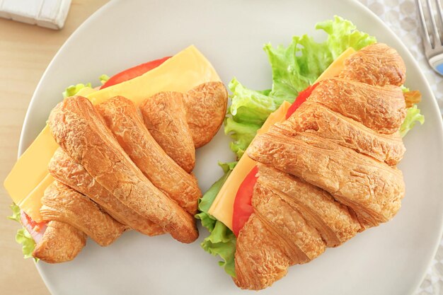 Plate with delicious croissant sandwiches on table closeup