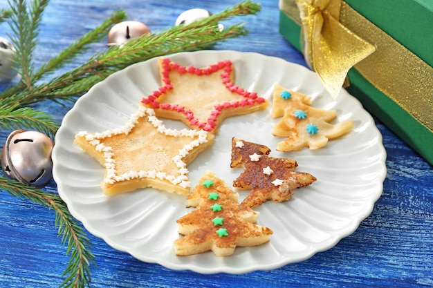 Plate with delicious fir trees and stars from pancakes on color wooden background