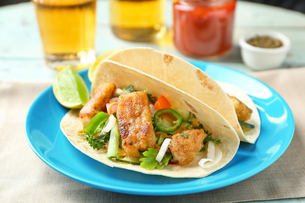 Plate with delicious fish tacos on table