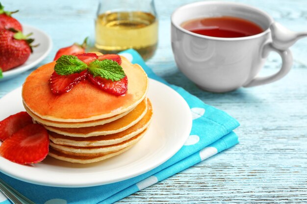 Plate with delicious pancakes on table