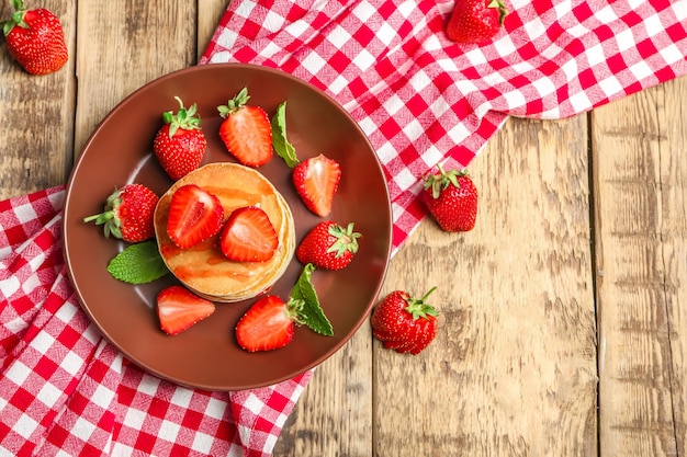 Plate with delicious pancakes on wooden background