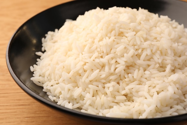 Plate with delicious rice on wooden table closeup