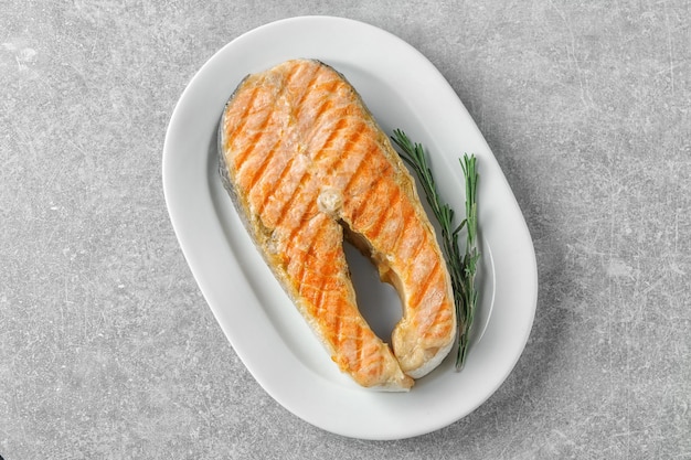 Photo plate with delicious salmon steak on table