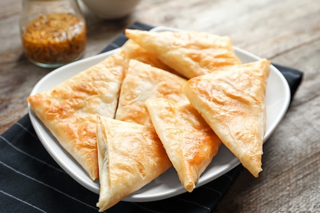 Plate with delicious samosas on table