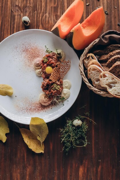 Plate with delicious tartare, toasted bread and salad on a wooden table.