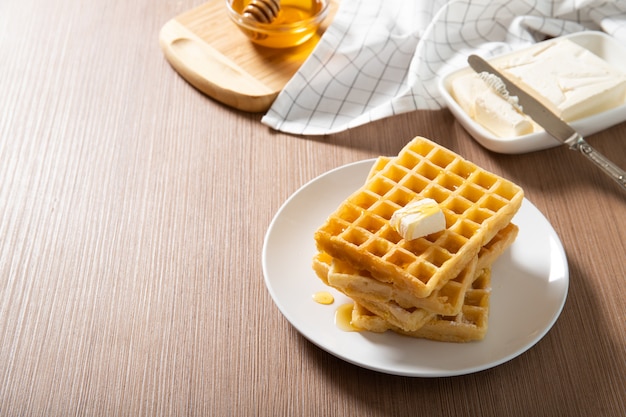 Foto piastra con deliziosi waffle con miele e una fetta di burro