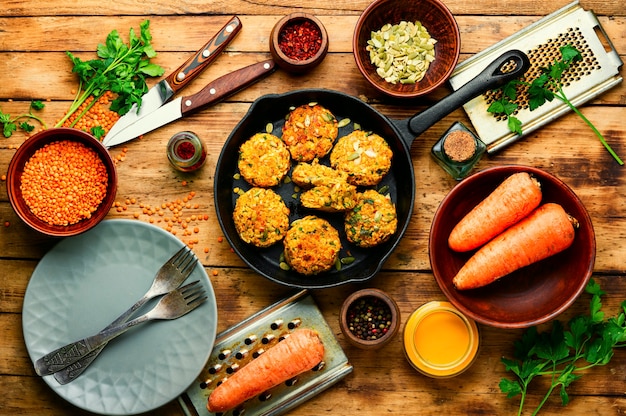 食餌療法の菜食主義者のレンチルおよびニンジンのカレットの皿。食事療法の食糧。木の素朴なテーブルの上の野菜のカツメ。