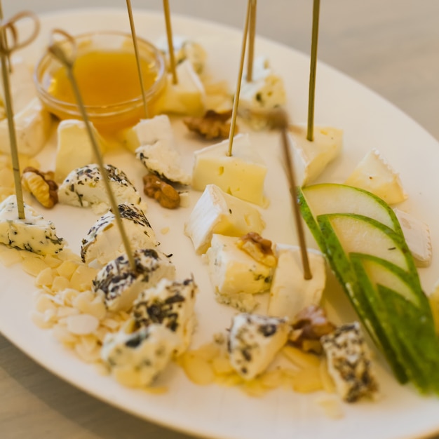 Plate with different types of cheese, honey, walnut and pear