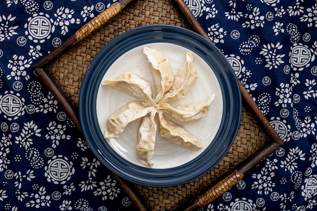 Photo plate with dim sum on a wooden stand on a blue and white floral background