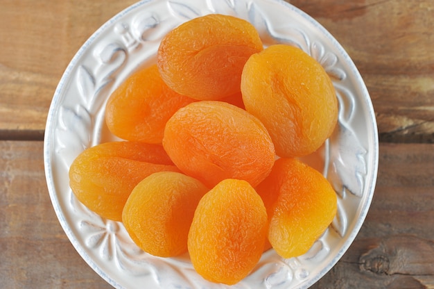 Plate with dried apricots   dried apricots on a wooden   - macro