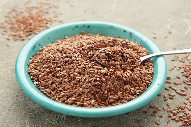 Plate with flax seeds on grey background