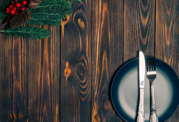 A plate with a fork and knife on it next to a pine branch.