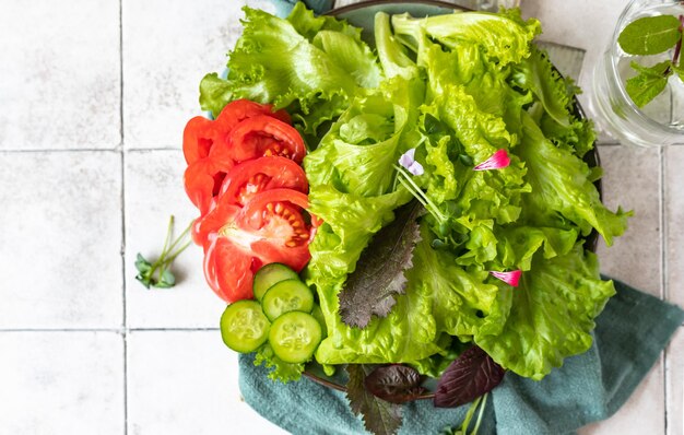 Plate with fresh green salad Mix of salad leaves with cucumber tomatoes and microgreen Top view