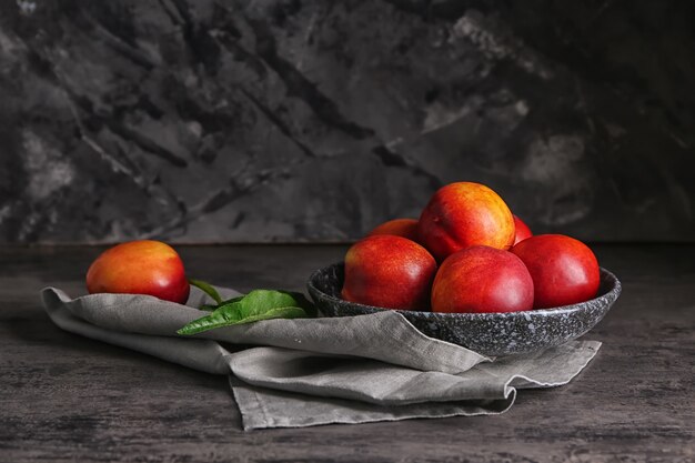 Plate with fresh peaches on dark table