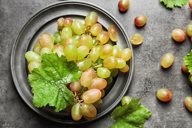 Plate with fresh ripe grapes on table