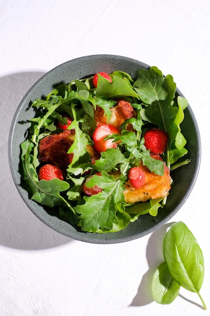 Plate with fresh salad of arugula, plants, cheese, basil and strawberry. Top view food.