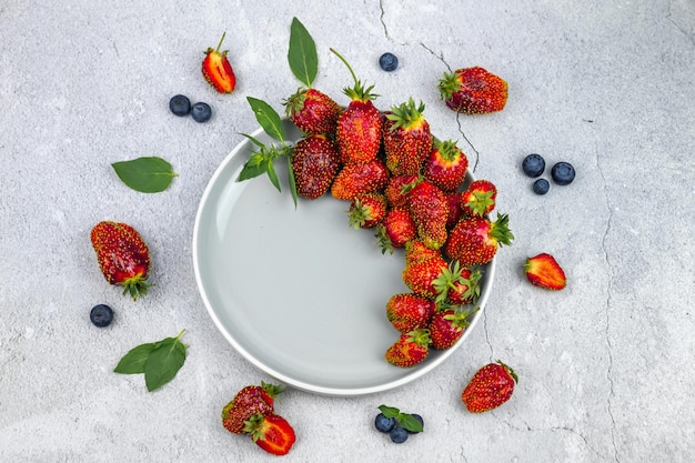 Plate with fresh strawberries on a gray concrete background