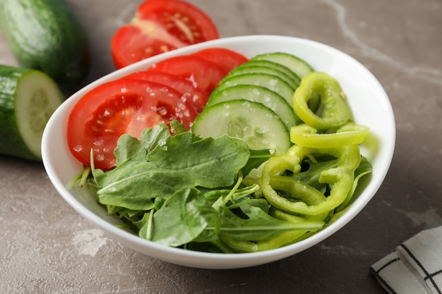 Plate with fresh vegetable slices on grey