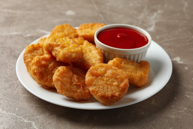 Photo plate with fried chicken nuggets and ketchup on gray table, close up