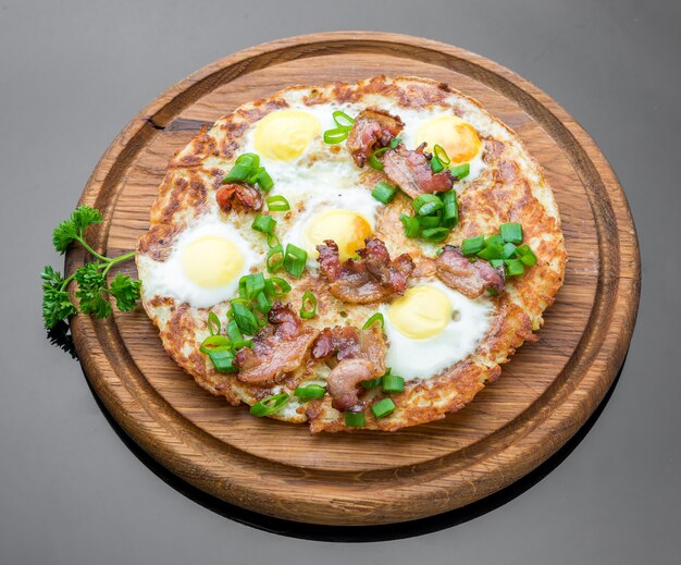 Plate with fried eggs, bacon, tomato and potato griddle cakes close up